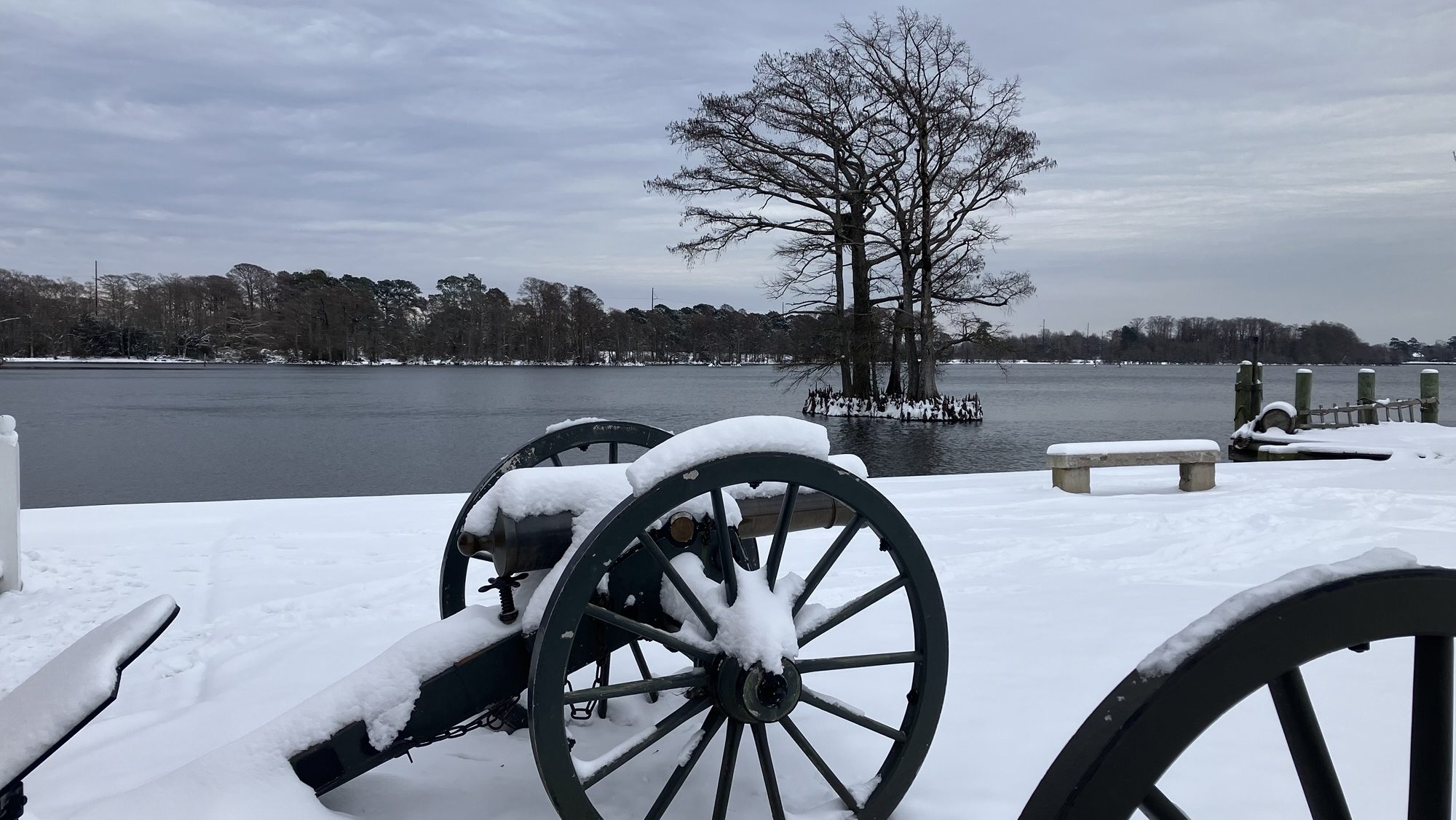 cannon and ground covered in snow with water in distance