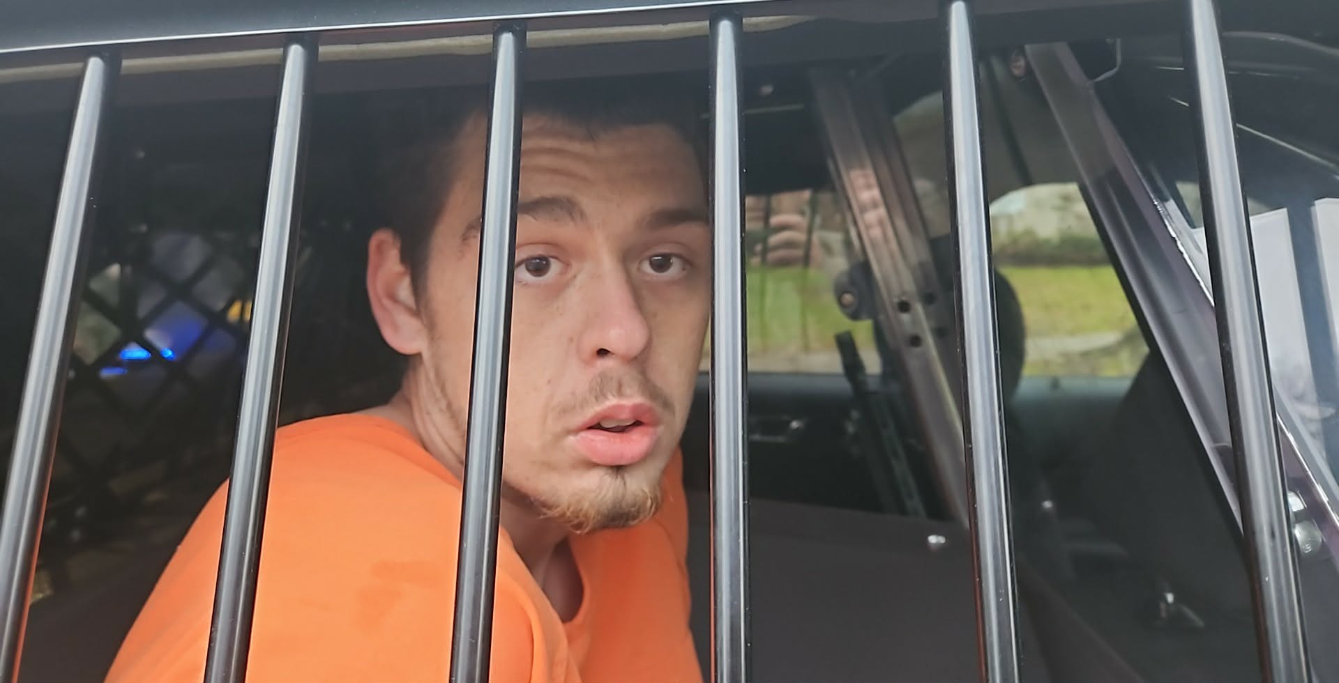 A man behind bars in a police cruiser.