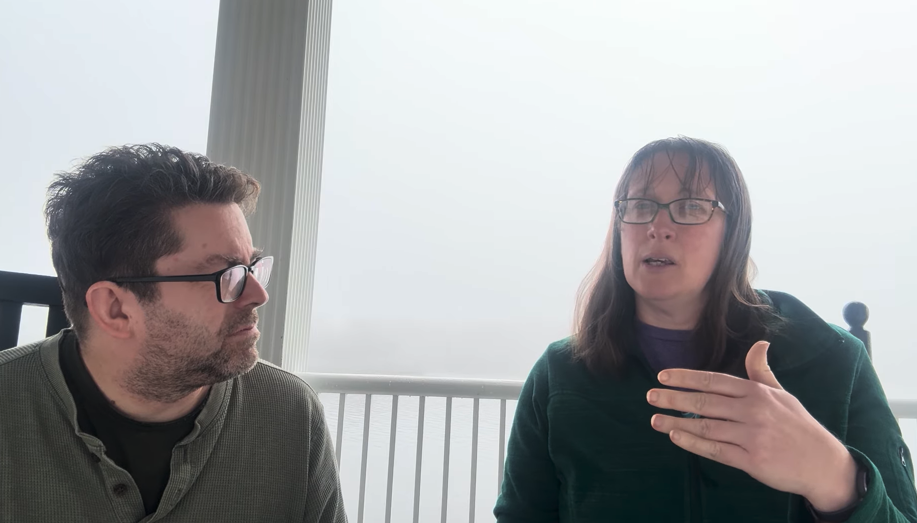 two people sitting on a porch with fog in the background